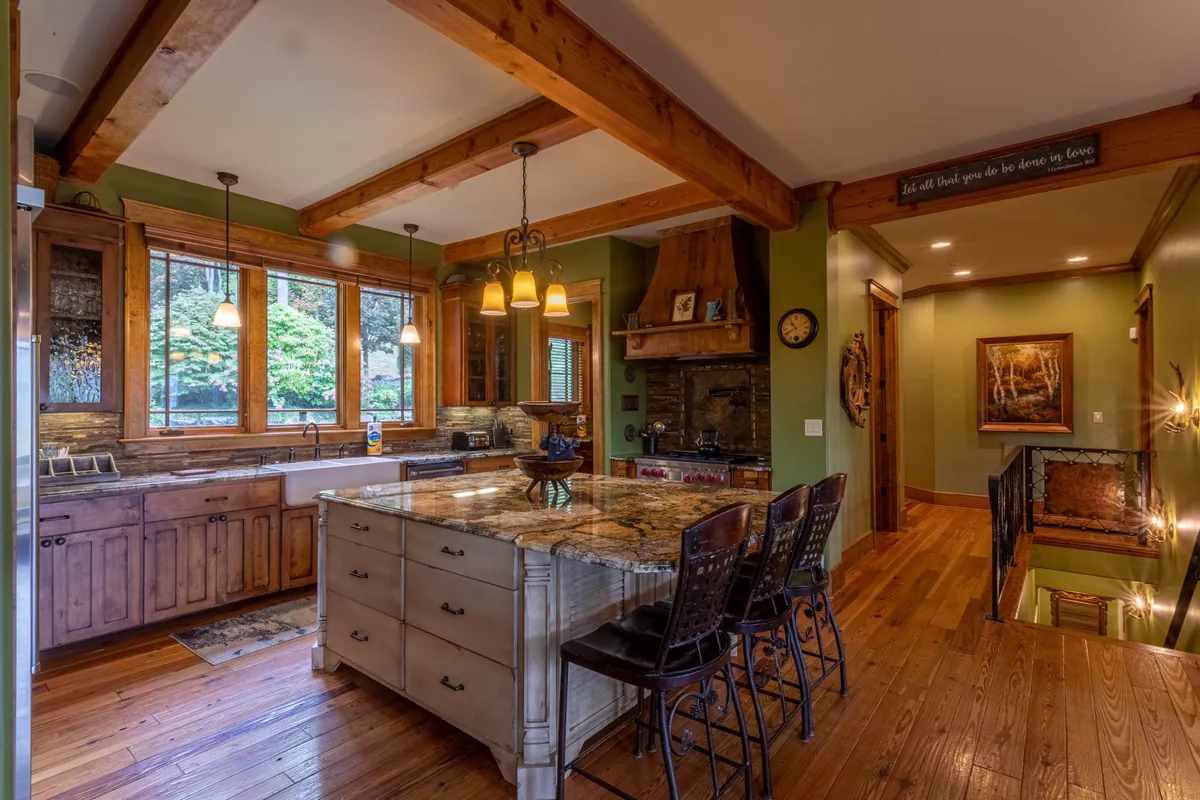 A chef-inspired kitchen featuring gleaming granite countertops, custom wooden cabinetry, and an island with seating. Large windows flood the space with natural light, and modern appliances—including a professional-grade cooktop—set the scene for memorable group meals and culinary creativity.