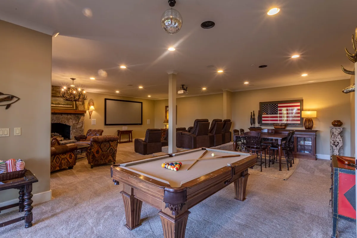 An inviting interior recreation space featuring a pool table, fireplace, comfortable seating, and a bar table. The setting is lively yet relaxed, ideal for group games, movie nights, and informal gatherings after a day of activities.