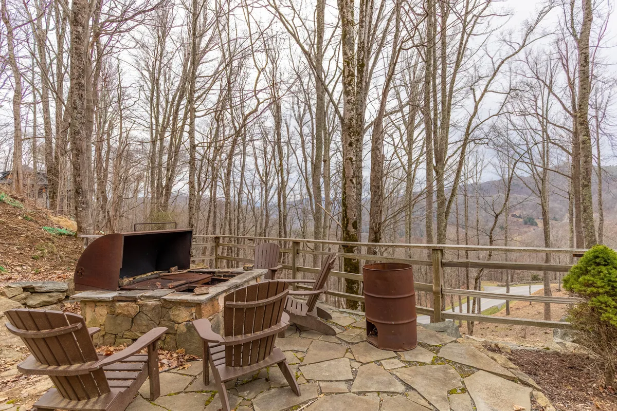 A fire pit surrounded by wooden chairs nestled amidst tall trees, exuding warmth and inviting guests to gather for storytelling or roasting s’mores. The natural setting reinforces the connection to the outdoors and communal experiences.