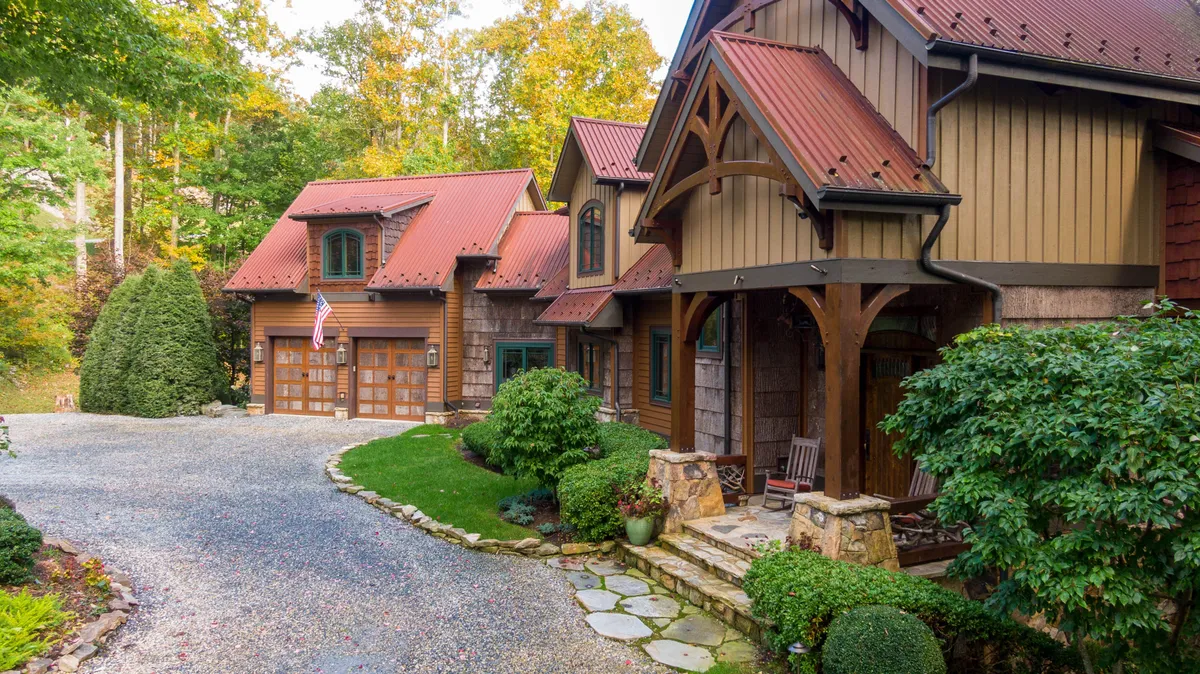 This image spotlights the main entrance of the home, with an inviting landscaped garden in the foreground and a spacious patio area. The scene suggests easy transitions between indoor comfort and outdoor relaxation, perfect for both people and pets to enjoy the mountain air.