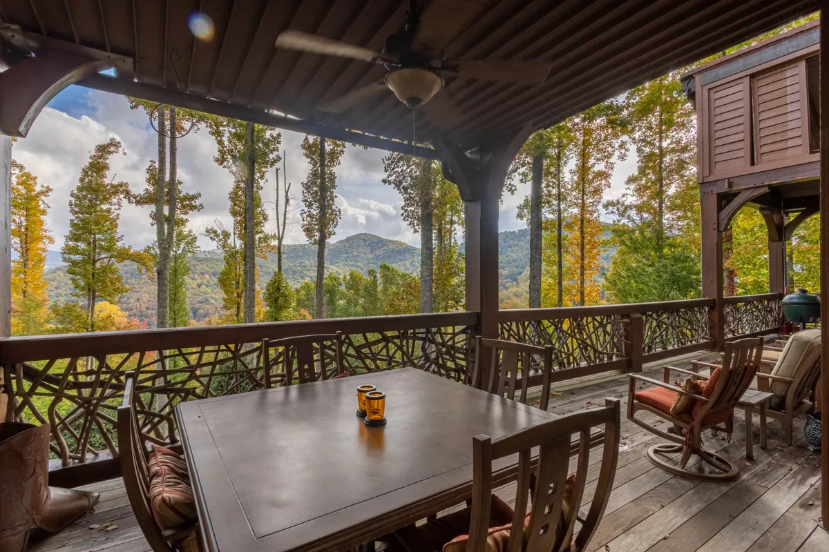 A tranquil outdoor setting with a table holding a coffee cup, surrounded by trees and offering a panoramic mountain view. The scene suggests a peaceful moment on a deck, ideal for morning coffee or sunset relaxation.